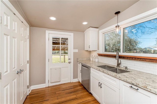 kitchen featuring backsplash, a sink, light wood-style floors, white cabinetry, and stainless steel dishwasher