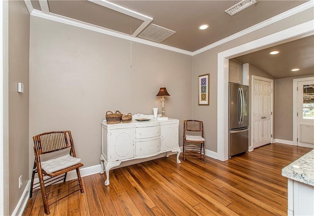 living area with baseboards, attic access, ornamental molding, and wood finished floors