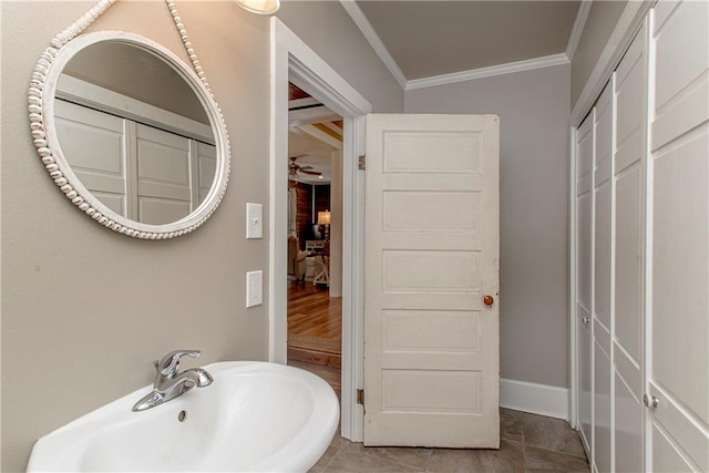 bathroom featuring crown molding, a sink, baseboards, and ceiling fan