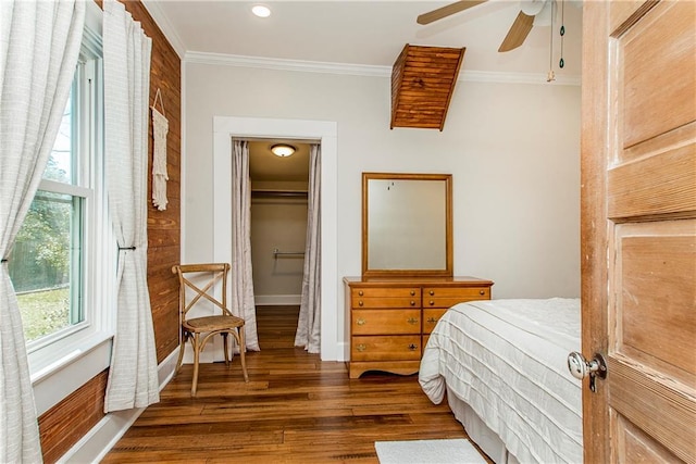 bedroom featuring baseboards, ceiling fan, wood finished floors, crown molding, and a closet