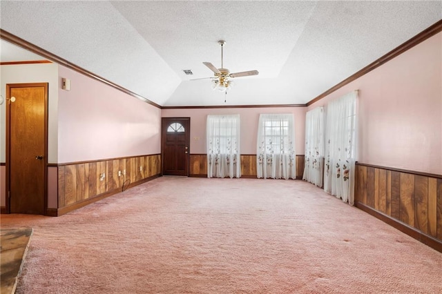 empty room with a wainscoted wall, carpet, a textured ceiling, and wood walls