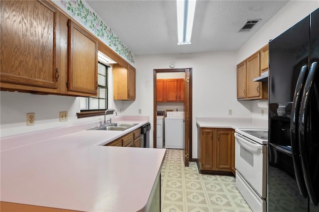 kitchen with brown cabinets, visible vents, washing machine and dryer, a sink, and black appliances