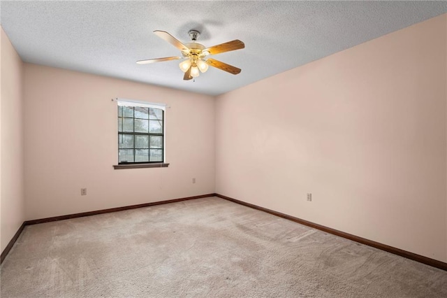 carpeted spare room featuring a ceiling fan, a textured ceiling, and baseboards