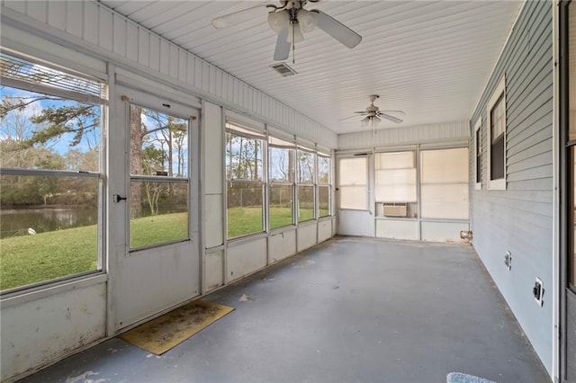 unfurnished sunroom featuring ceiling fan, a wealth of natural light, a water view, and visible vents