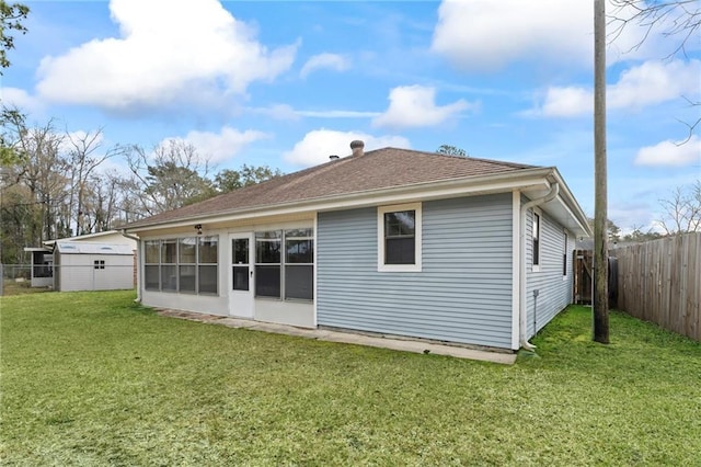 back of property featuring a sunroom, a fenced backyard, roof with shingles, and a yard