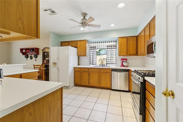 kitchen with visible vents, brown cabinets, stainless steel appliances, light countertops, and a sink