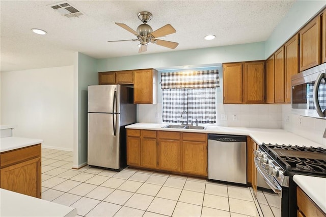 128 Sumner St, Covington, LA 70433 - kitchen with appliances with stainless steel finishes, a sink, ceiling fan, brown cabinets, and a textured ceiling