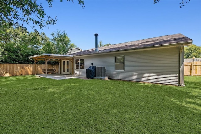 rear view of house with a fenced backyard, a lawn, and a patio