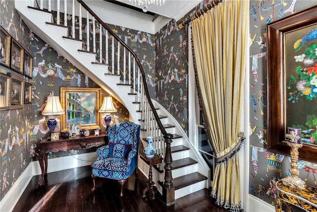 stairway with wood finished floors, baseboards, and wallpapered walls