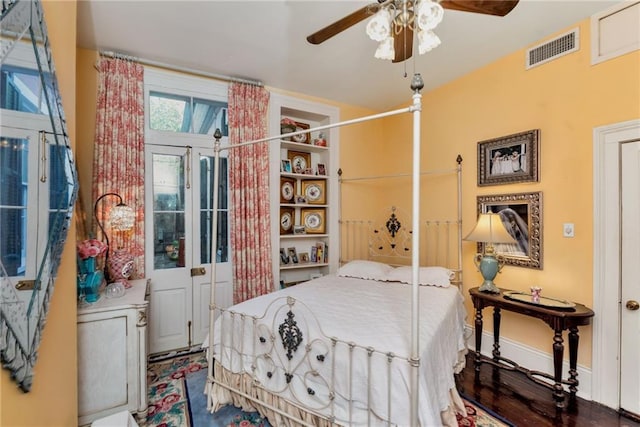 bedroom featuring a ceiling fan, visible vents, baseboards, and wood finished floors