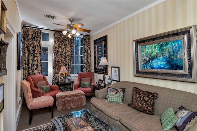 living room featuring crown molding, a ceiling fan, visible vents, and wallpapered walls