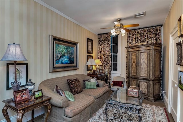 living area with wallpapered walls, visible vents, baseboards, ceiling fan, and ornamental molding