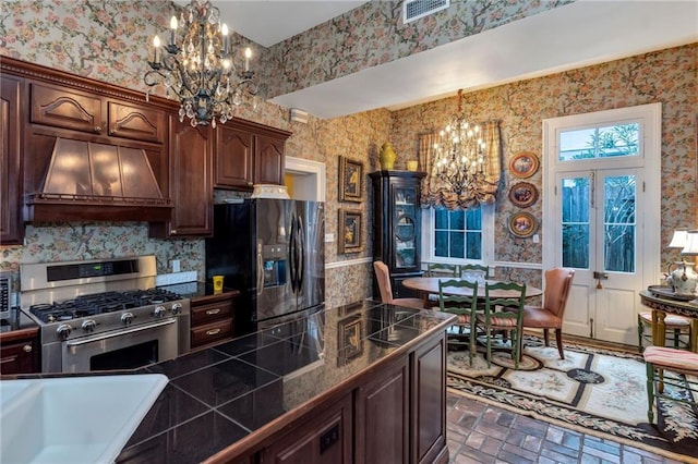 kitchen featuring custom range hood, visible vents, stainless steel appliances, and a notable chandelier