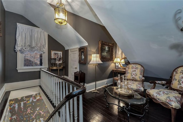 living area featuring lofted ceiling, hardwood / wood-style flooring, baseboards, and an upstairs landing