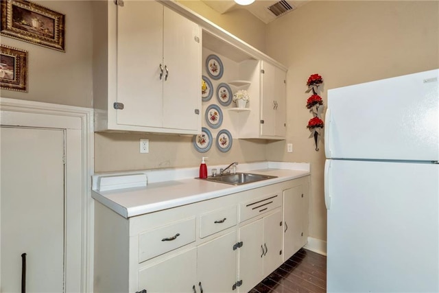 kitchen featuring visible vents, freestanding refrigerator, light countertops, open shelves, and a sink