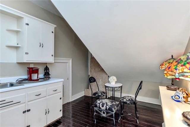 dining space featuring vaulted ceiling, baseboards, and dark wood finished floors