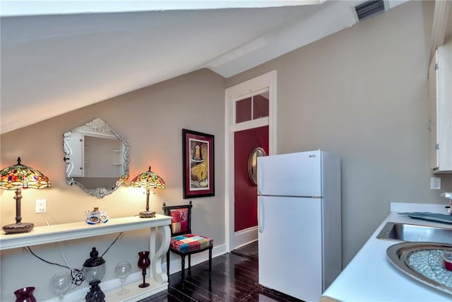 kitchen featuring lofted ceiling, visible vents, dark wood-type flooring, freestanding refrigerator, and a sink