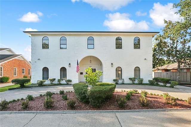 view of front of home with concrete driveway, brick siding, and fence