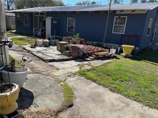 rear view of property with a patio area, metal roof, and a lawn