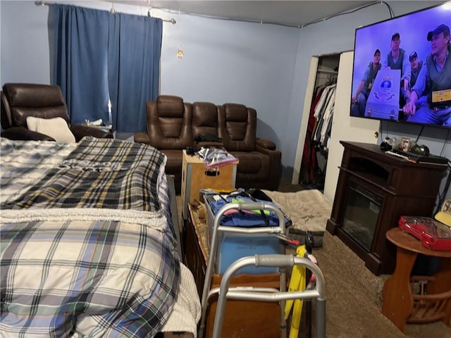 bedroom featuring carpet floors, a glass covered fireplace, and a closet