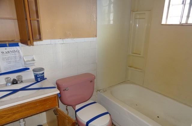 bathroom with tile walls, toilet, and vanity