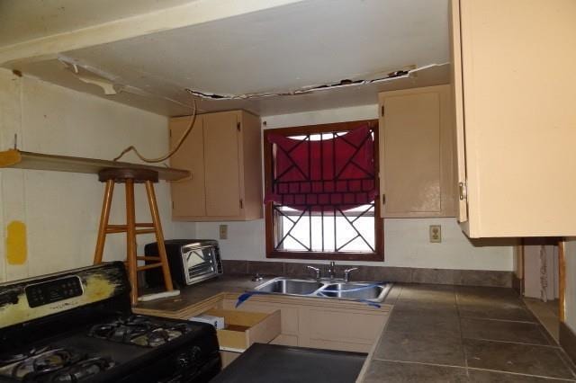 kitchen with tile patterned flooring, stainless steel range with gas stovetop, a sink, and tile countertops