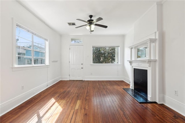 unfurnished living room featuring a fireplace with raised hearth, hardwood / wood-style floors, a wealth of natural light, and visible vents