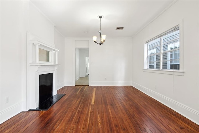 unfurnished living room featuring dark wood-style floors, a notable chandelier, a fireplace with raised hearth, visible vents, and ornamental molding