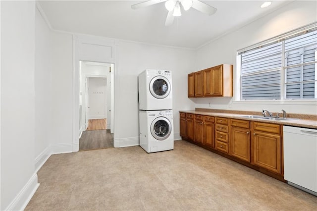 washroom with a ceiling fan, ornamental molding, a sink, stacked washing maching and dryer, and laundry area