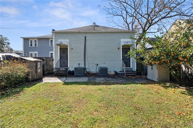 back of house featuring entry steps, a yard, cooling unit, and fence