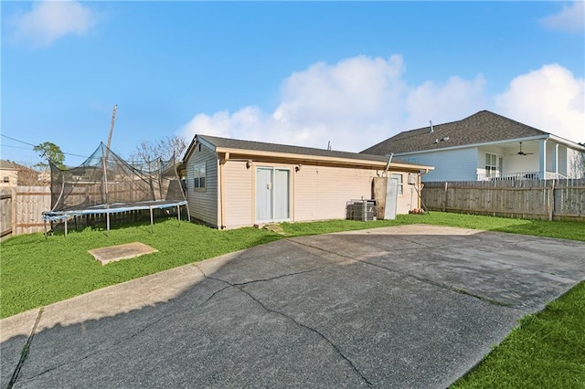 rear view of house featuring a fenced backyard, cooling unit, a lawn, a trampoline, and a patio area