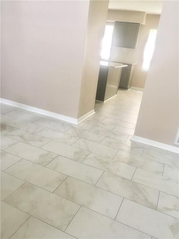 spare room featuring marble finish floor and baseboards