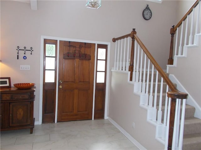 foyer entrance with stairs, marble finish floor, and baseboards