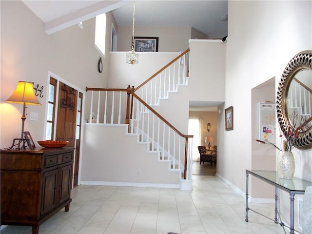 entryway featuring stairs, a high ceiling, an inviting chandelier, and baseboards