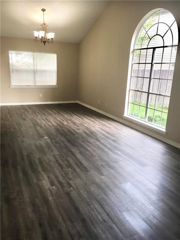 spare room with vaulted ceiling, dark wood finished floors, and a notable chandelier