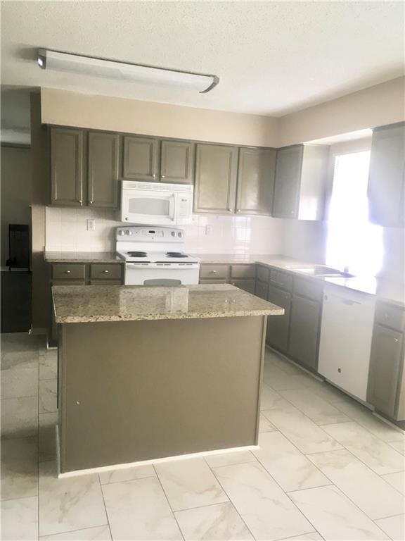 kitchen with light stone counters, white appliances, marble finish floor, and backsplash