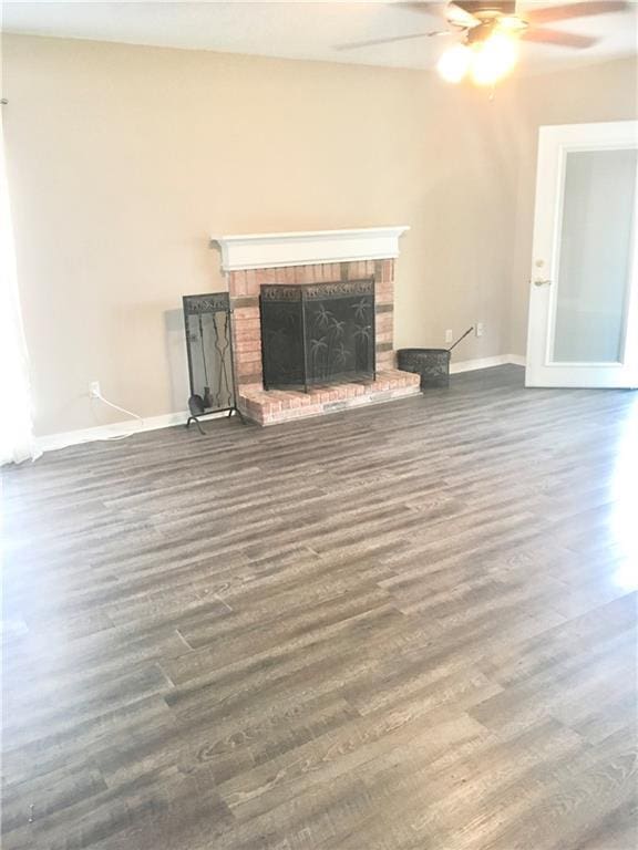 unfurnished living room with a fireplace, baseboards, and wood finished floors