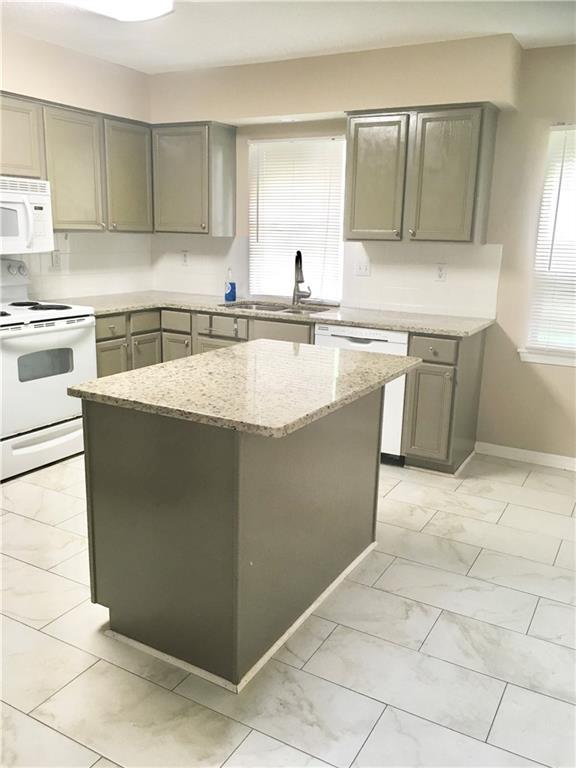 kitchen with marble finish floor, white appliances, gray cabinets, and light stone countertops