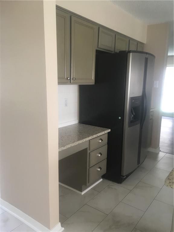 kitchen featuring marble finish floor, baseboards, light countertops, and stainless steel fridge with ice dispenser