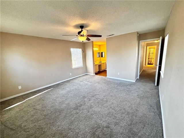 unfurnished bedroom with baseboards, visible vents, ensuite bath, a textured ceiling, and carpet floors