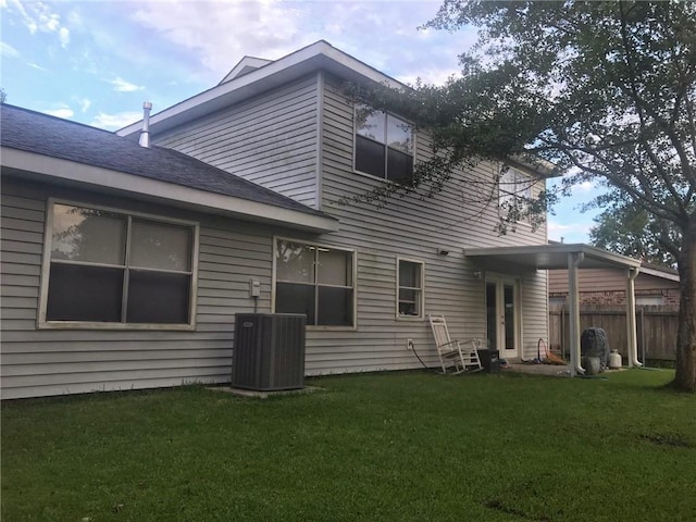 back of property with a yard, fence, and central air condition unit