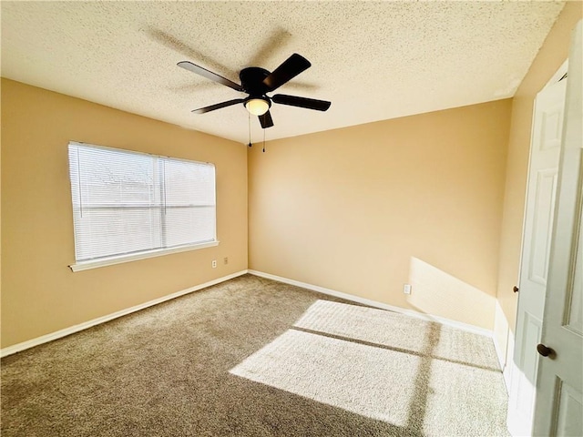 carpeted empty room featuring a textured ceiling, ceiling fan, and baseboards