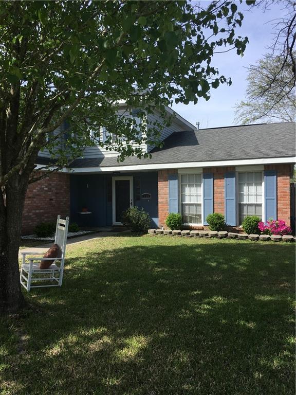 view of front of home with a shingled roof, brick siding, and a front lawn