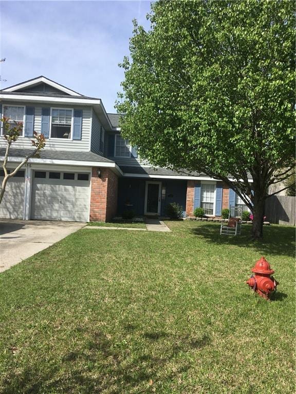 view of front of house featuring a garage, driveway, brick siding, and a front lawn