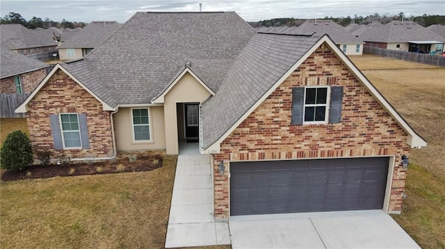 traditional home with a garage, brick siding, concrete driveway, and a front yard