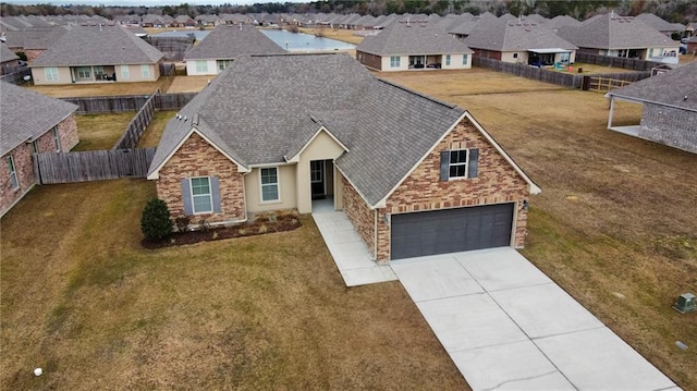 view of front of home featuring a residential view, brick siding, driveway, and fence private yard