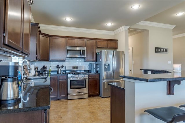 kitchen featuring a breakfast bar area, ornamental molding, a sink, stainless steel appliances, and backsplash