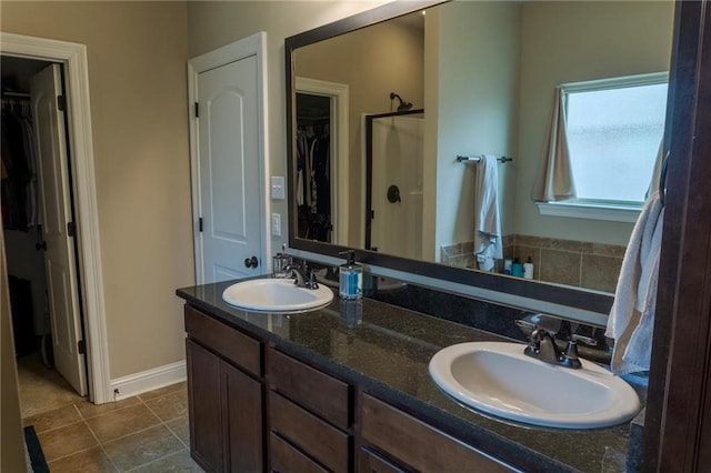 bathroom featuring double vanity, a walk in closet, and a sink