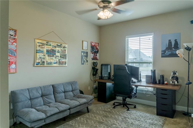 carpeted office space featuring ceiling fan and baseboards