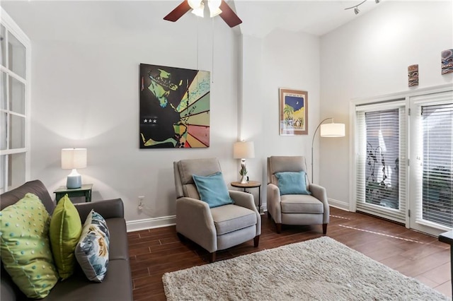 living area with ceiling fan, a high ceiling, baseboards, and wood finished floors